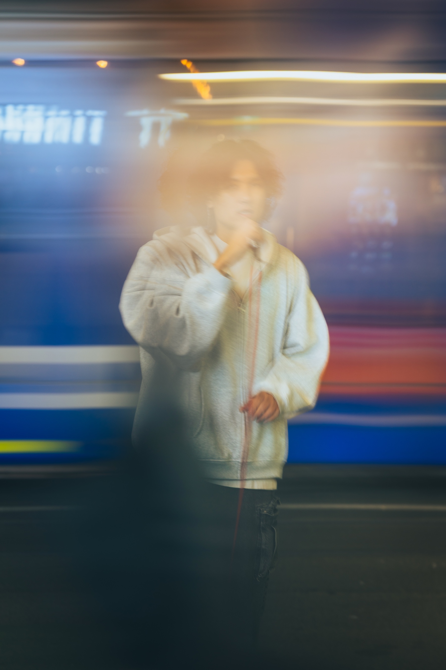 A soft, motion-blurred portrait of KUMA busking on the street.