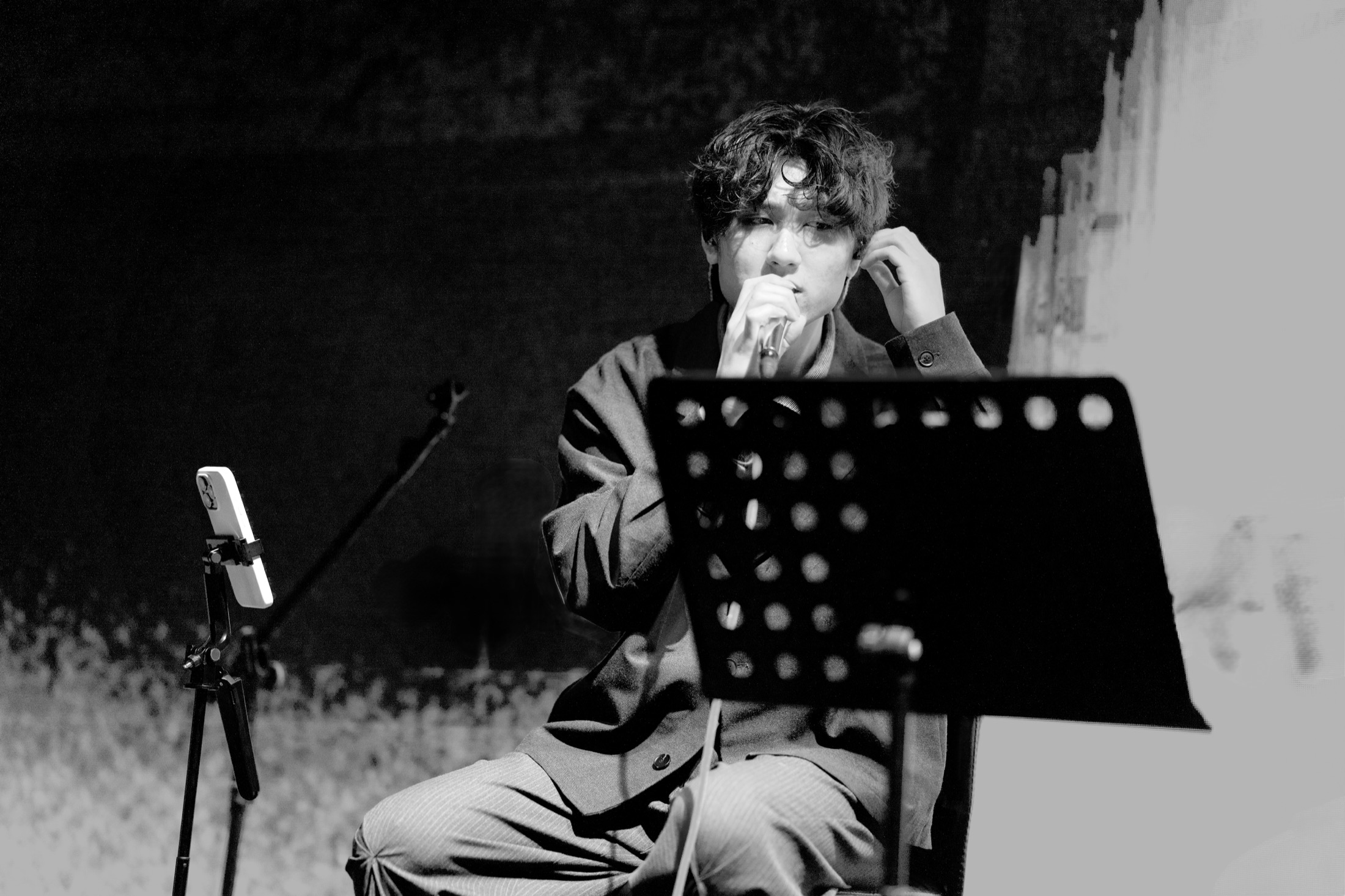 KUMA adjusting an earpiece beside a music stand.