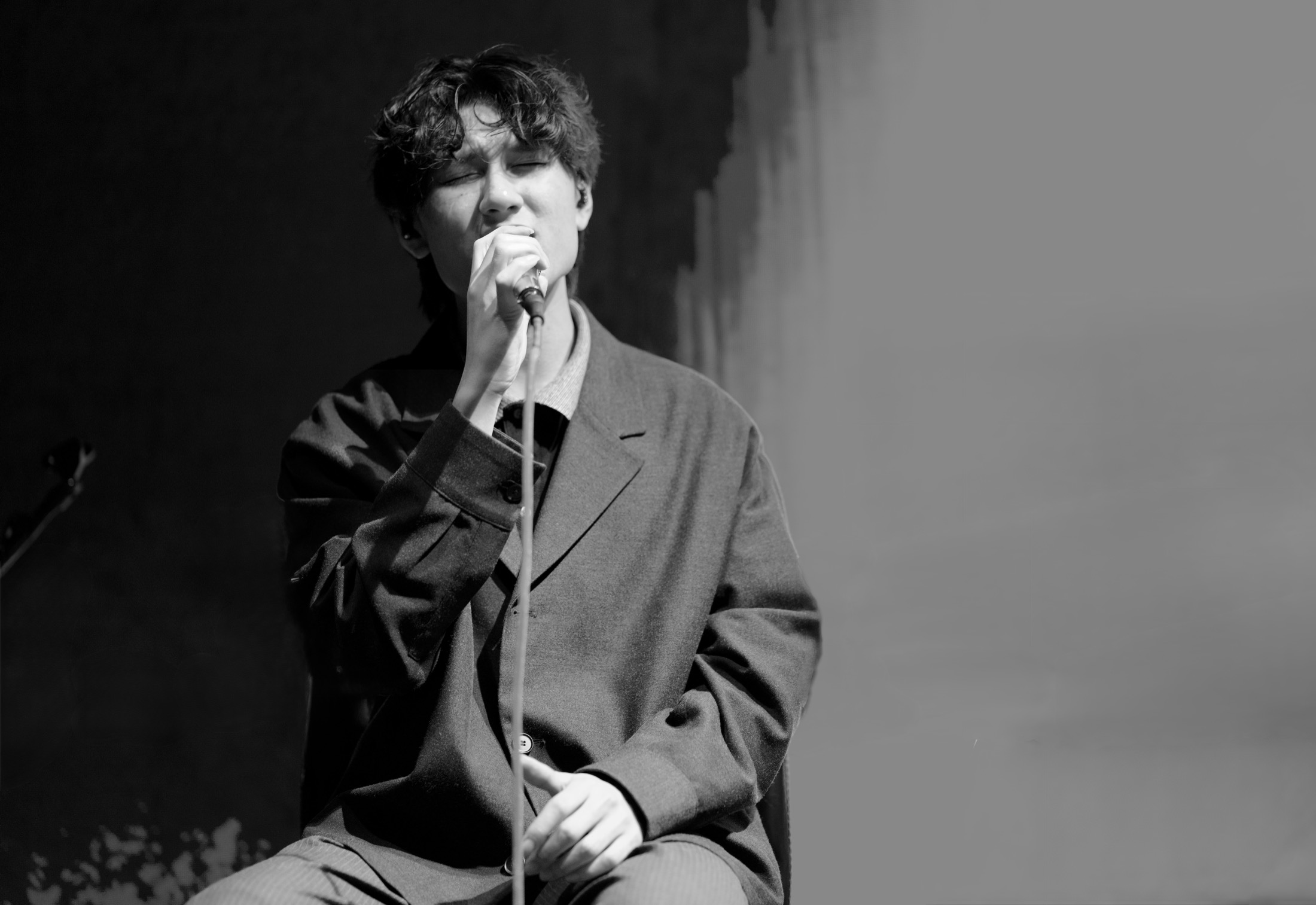 KUMA singing with eyes closed, captured in monochrome.