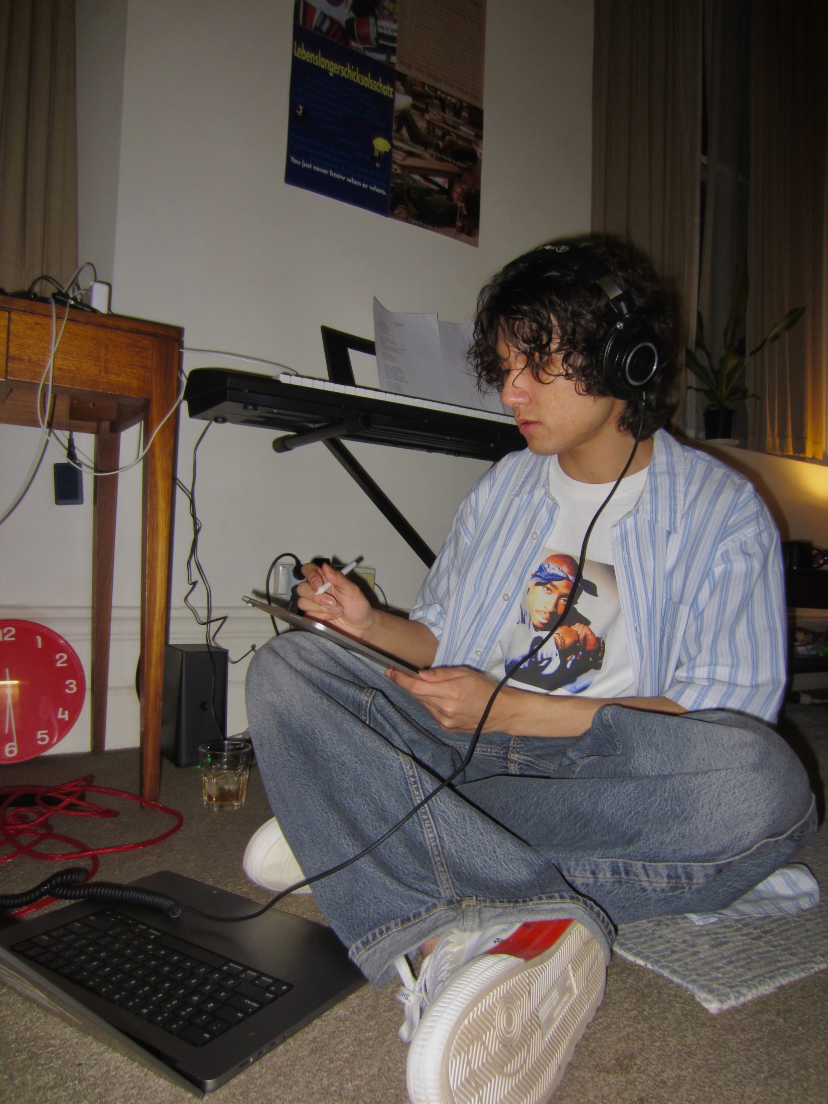 KUMA seated on the floor writing while wearing headphones.